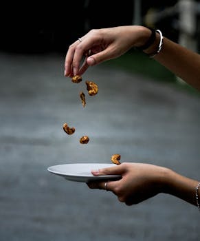 A creative shot of nuts falling into a plate held by hands, showcasing motion and dexterity.