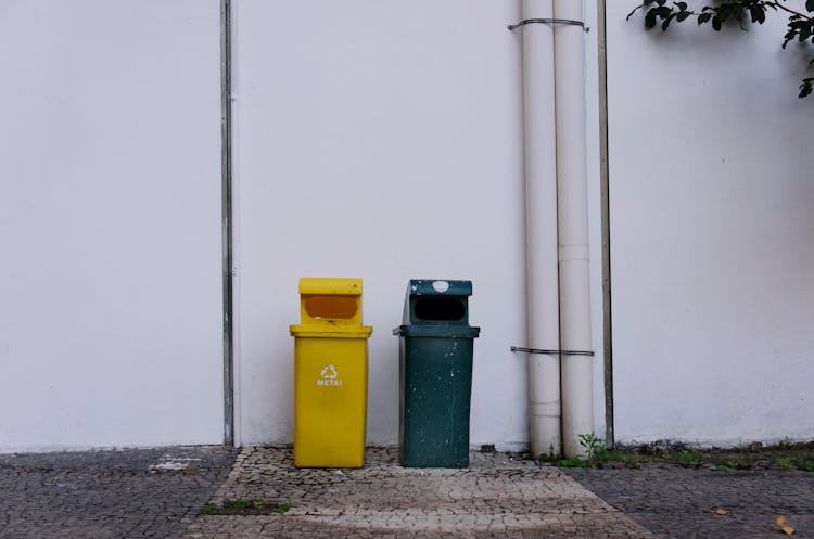 Trash Bins Beside A White Wall