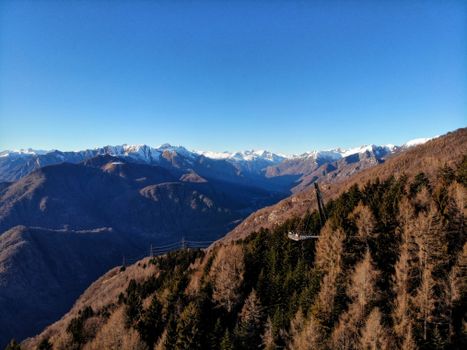 Breathtaking aerial view of mountain ranges with snowy peaks under clear blue sky.