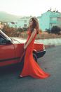 Woman in Red Sleeveless Dress Leaning on Red Car