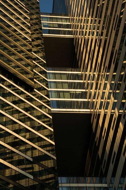 Free Close-up of a modern skyscraper's facade with reflections and sunlight at dusk. Stock Photo