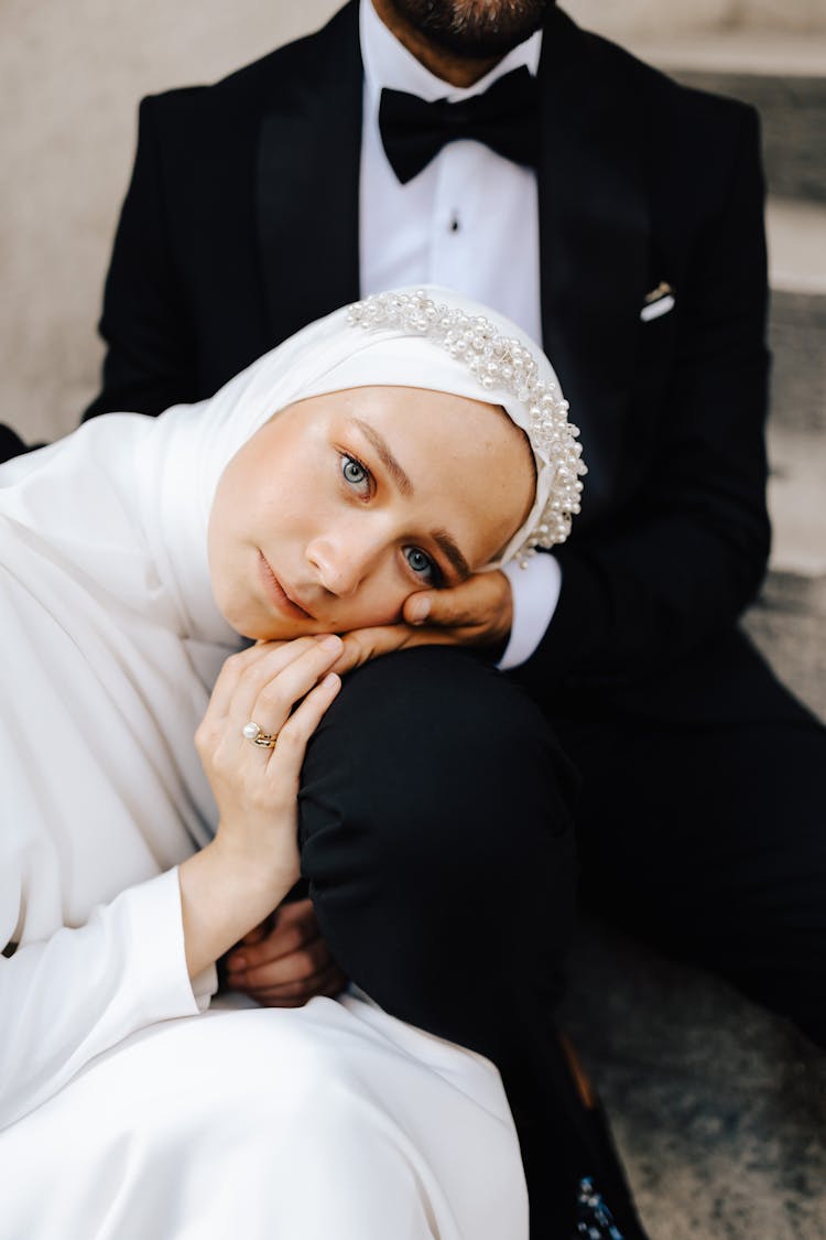 Portrait Of Hijabi Bride Laying On Grooms Lap