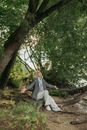 Woman in Gray Long Sleeve Shirt and White Pants Sitting on Tree Log