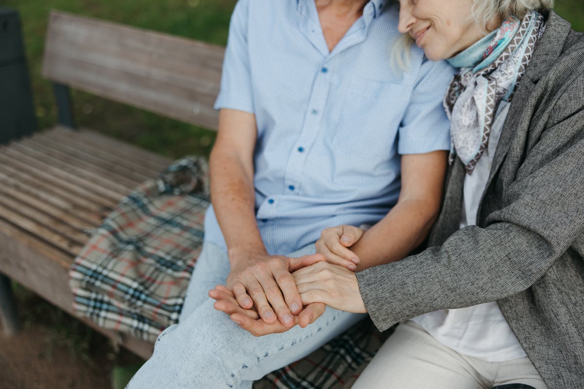 Elderly couple sitting on a bench symbolizing care and companionship