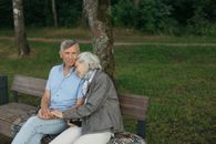 Woman in Gray Long Sleeve Shirt Sitting on Brown Wooden Bench