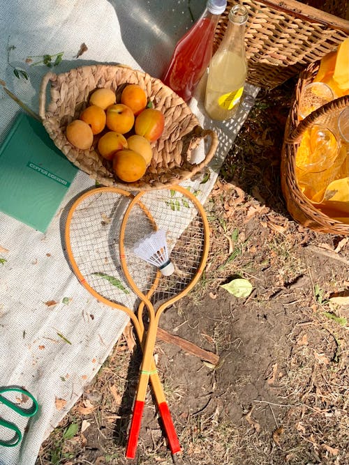 Free Fruits on Woven Basket Beside a Badminton Rockets Stock Photo