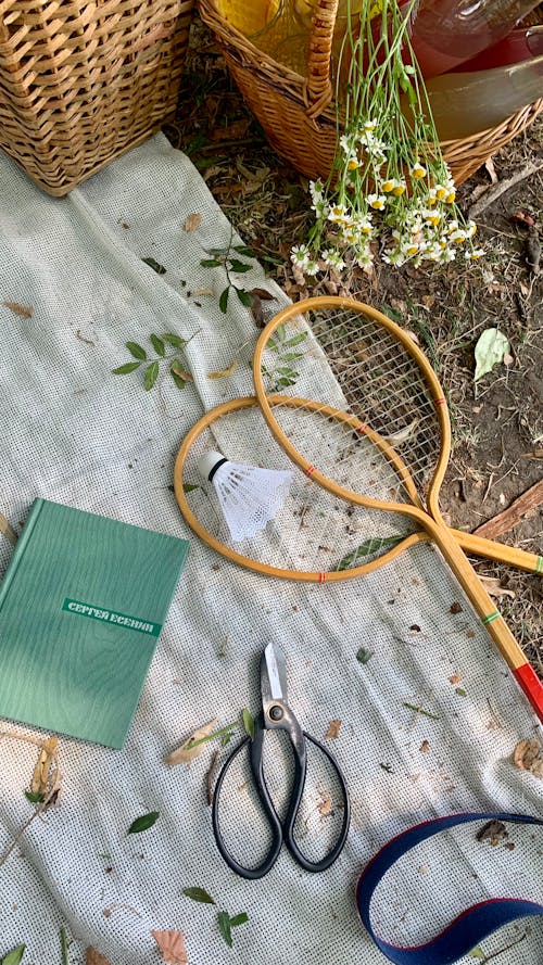 Free Badminton Rackets Beside a Notebook and Scissors on a White Fabric Stock Photo