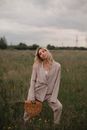 Woman in Gray Coat Holding Brown Wicker Basket on Green Grass Field