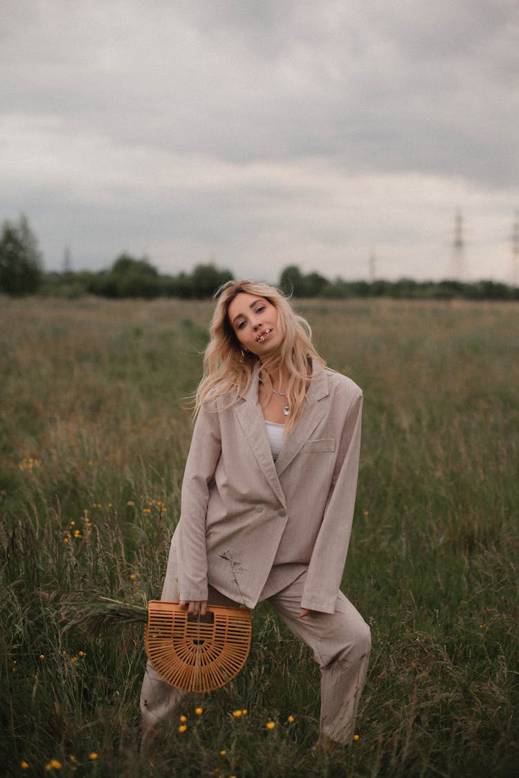 A Blonde Woman In Beige Suit Standing On The Grass