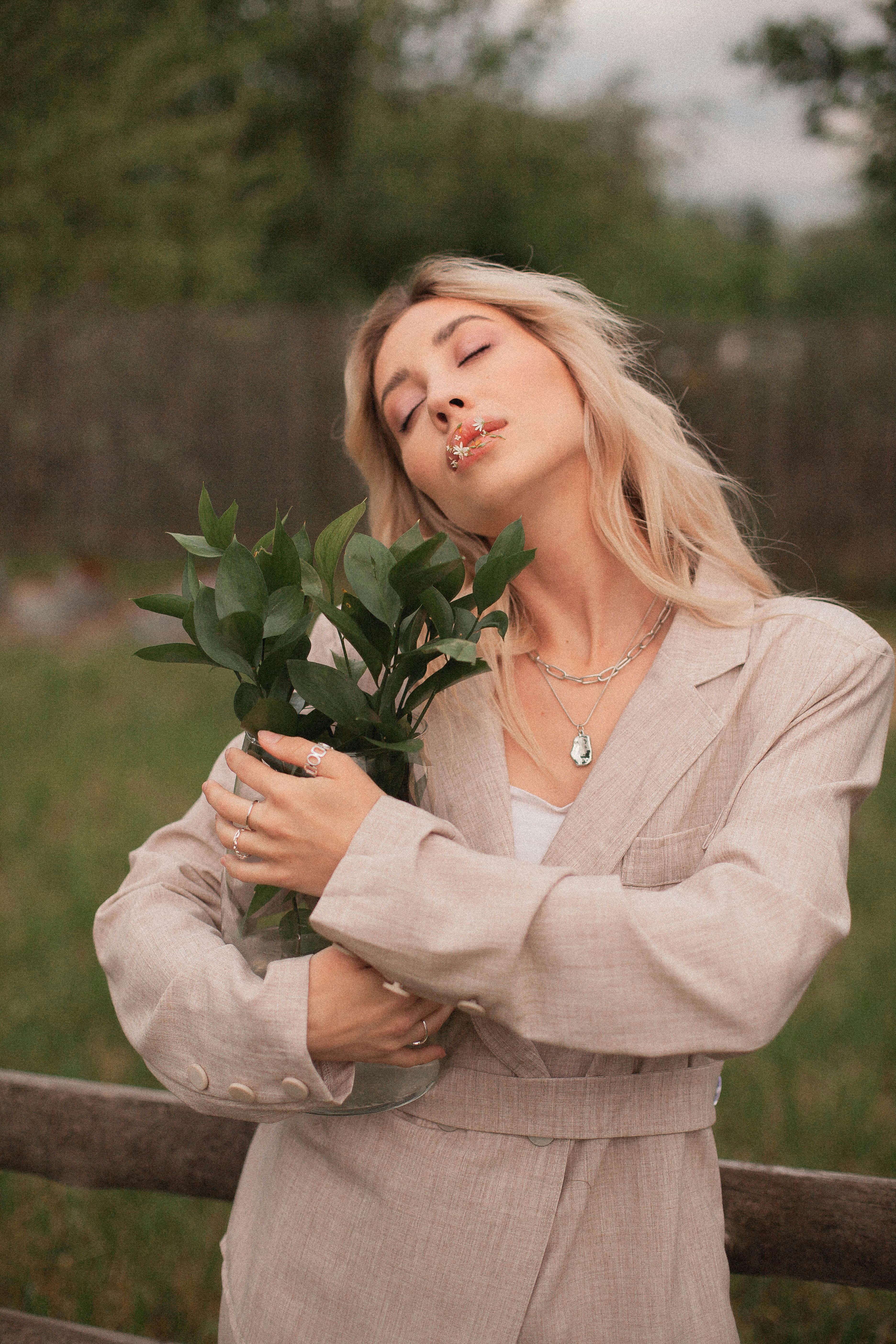 A serene moment with a woman holding plants outdoors, showcasing tranquility and natural beauty.