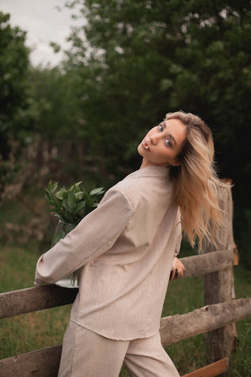 Woman in a Beige Blazer Posing Near a Wooden Fence