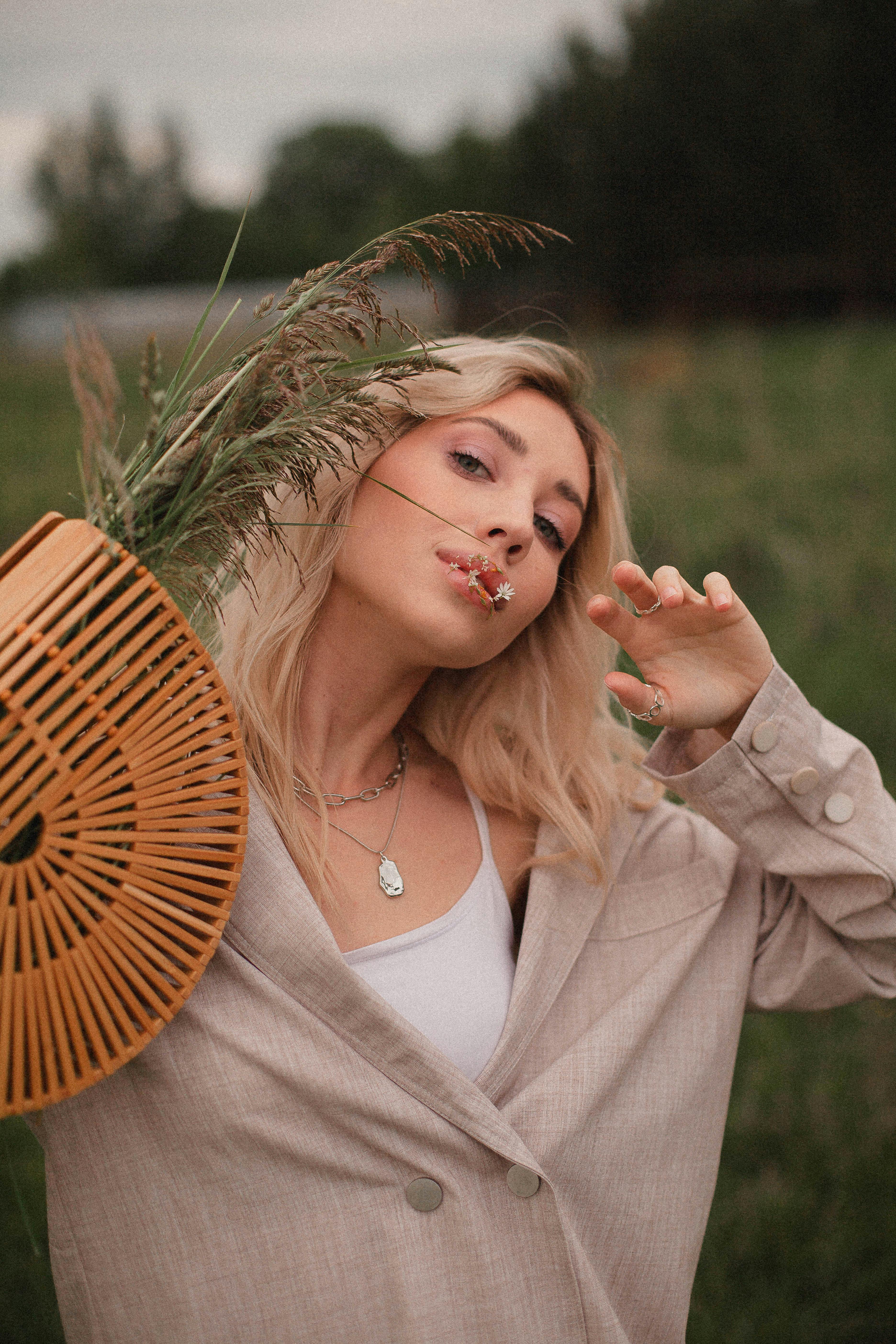 Free Fashionable woman in natural setting with rattan handbag, showcasing modern style. Stock Photo