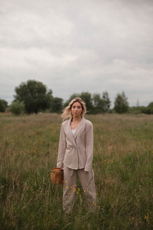 Woman in a Beige Blazer Standing on a Grass Field