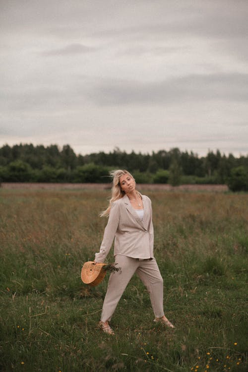 Woman with a Bag Posing on a Grass Field