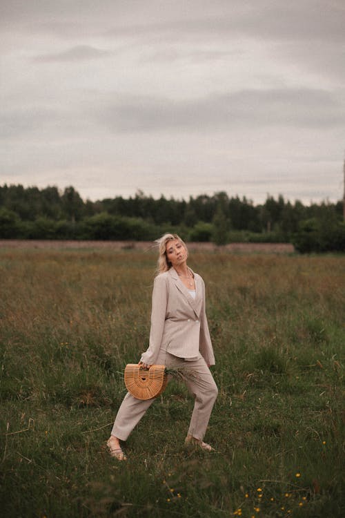 Woman with a Brown Bag Posing on a Grass Field