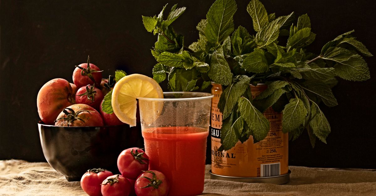 A refreshing glass of tomato juice with fresh basil, mint, and a slice of lemon on a rustic table. - Evidence evidence guide for tomato juice blood pressure meta-analysis