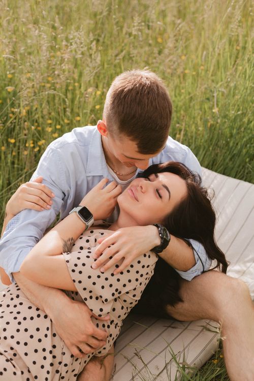 Free A couple enjoys a romantic moment in a sunlit meadow, embracing and smiling. Stock Photo