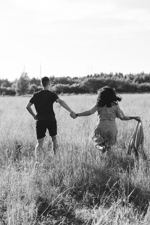 Free A couple walking hand in hand through a grassy meadow. Monochrome image. Stock Photo