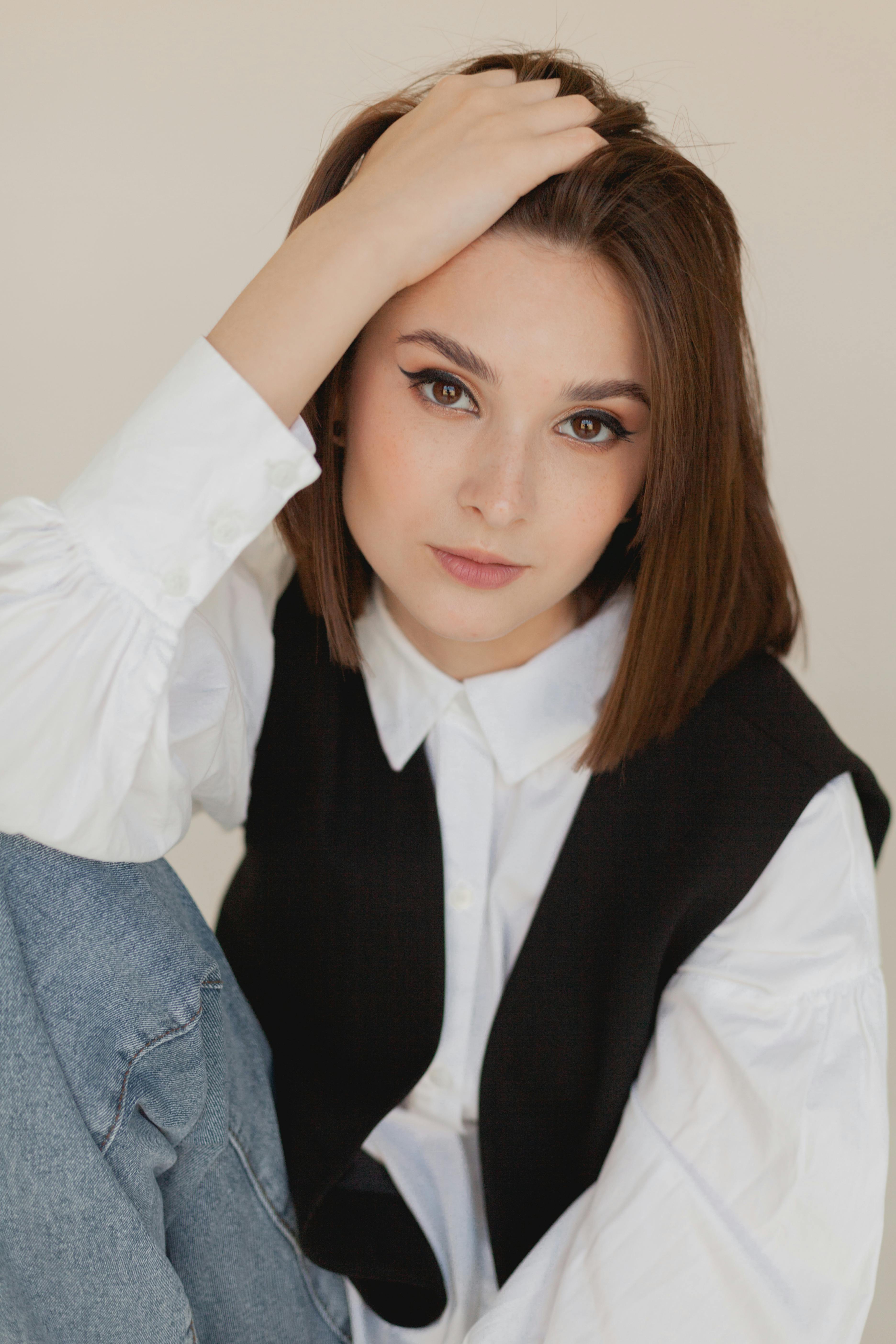A stylish woman poses elegantly in a studio with a casual yet fashionable outfit.