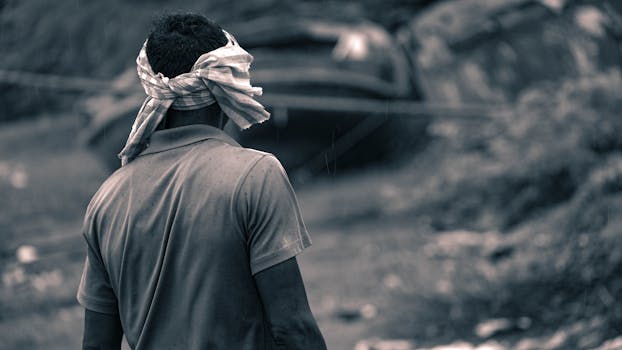 Back view of a man outdoors, captured in monochrome, with rain falling softly.