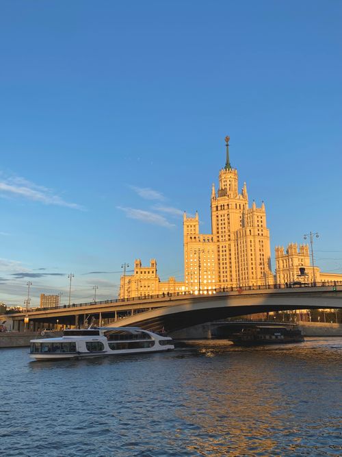 Free Scenic view of the Kotelnicheskaya Embankment Building and river with a ferry at sunset in Moscow, Russia. Stock Photo