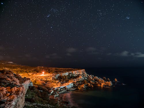 夜间在云层和天空下的水体附近的岩石峭壁