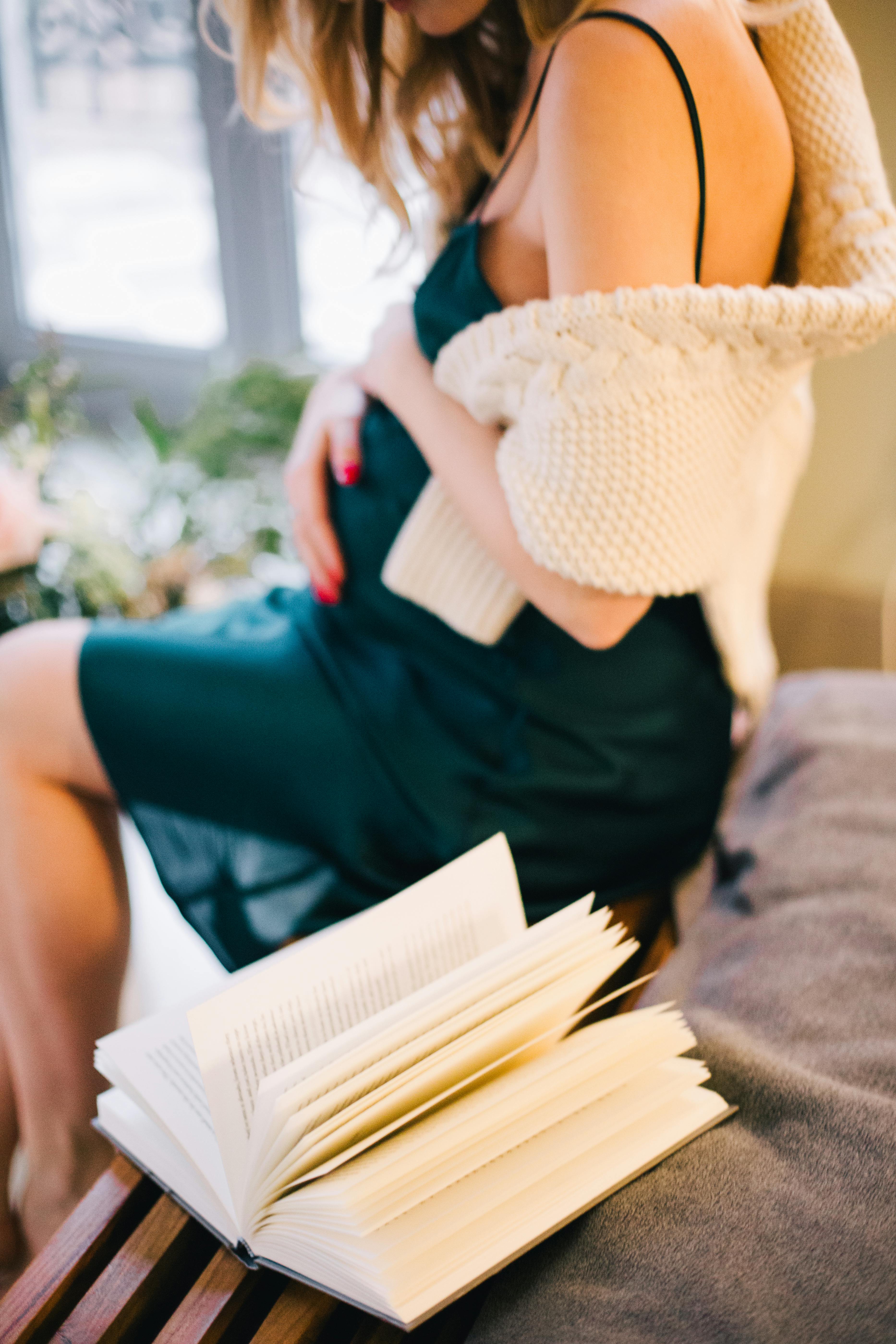 Schwangere Frau sitzt neben Buch | Quelle: Pexels