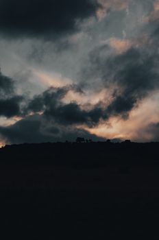 Dark clouds over a silhouetted landscape at twilight, capturing the drama of nature.