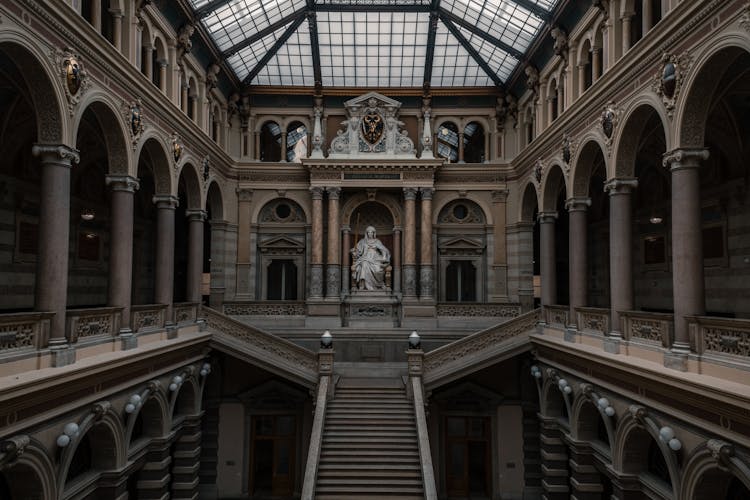 An Elegant Interior Design With A Statue Of A Woman Sitting Near Staircase