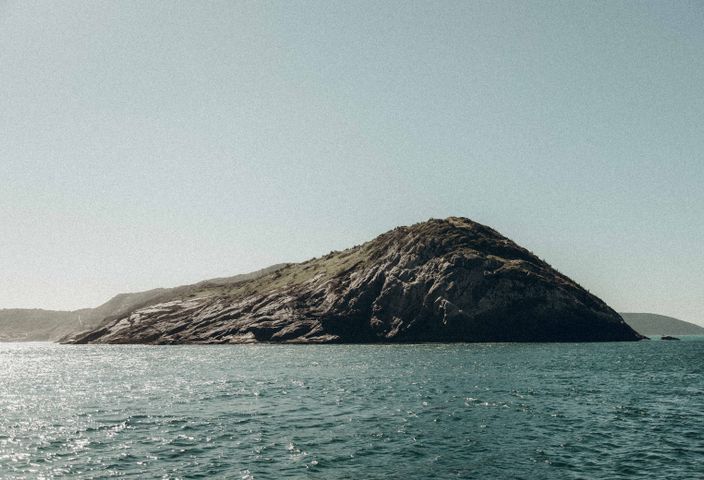 Breathtaking view of an island with rocky terrain surrounded by the sea in Arraial do Cabo, Brazil.