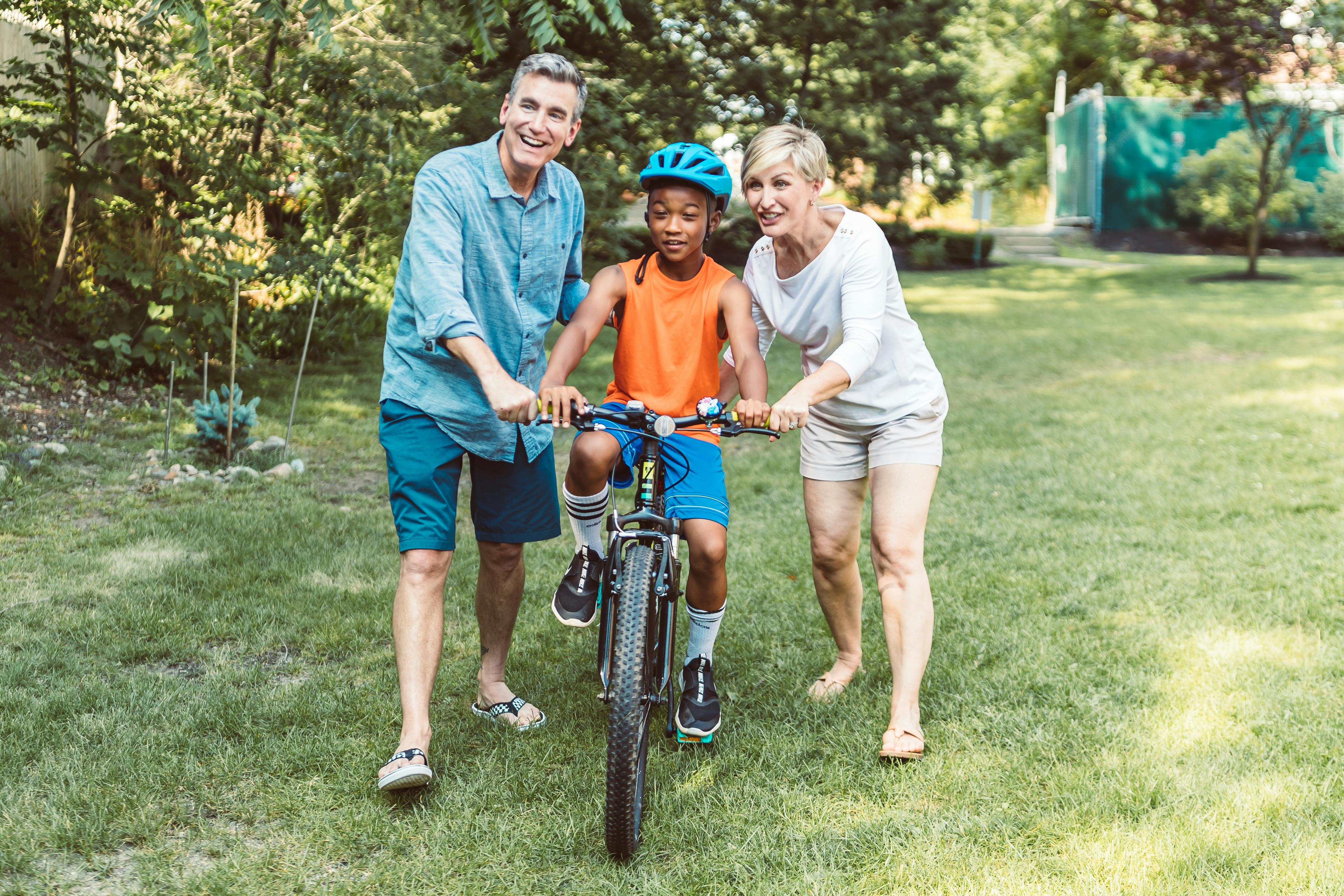 man and woman helping a boy riding a bicycle