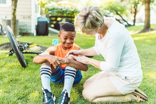 Free Mom Putting Band-Aid on Her Son's Knee Stock Photo