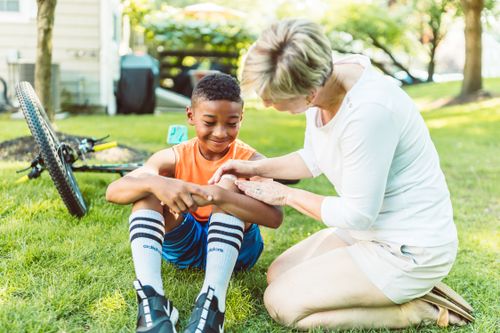 Free A loving mother tends to her son's minor injury during a playful outdoor moment. Stock Photo