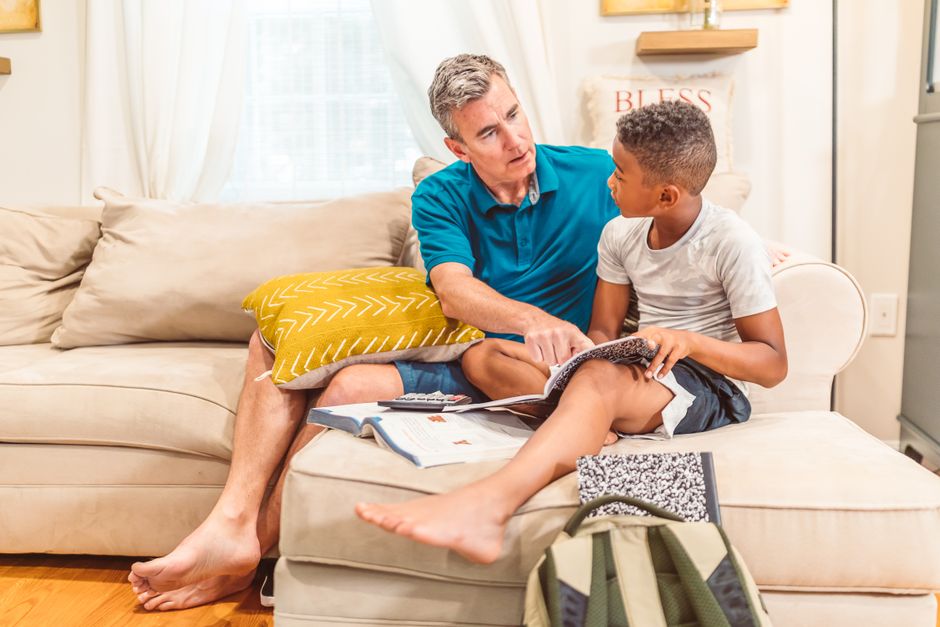 A father and son bonding over books in a cozy living room setting.