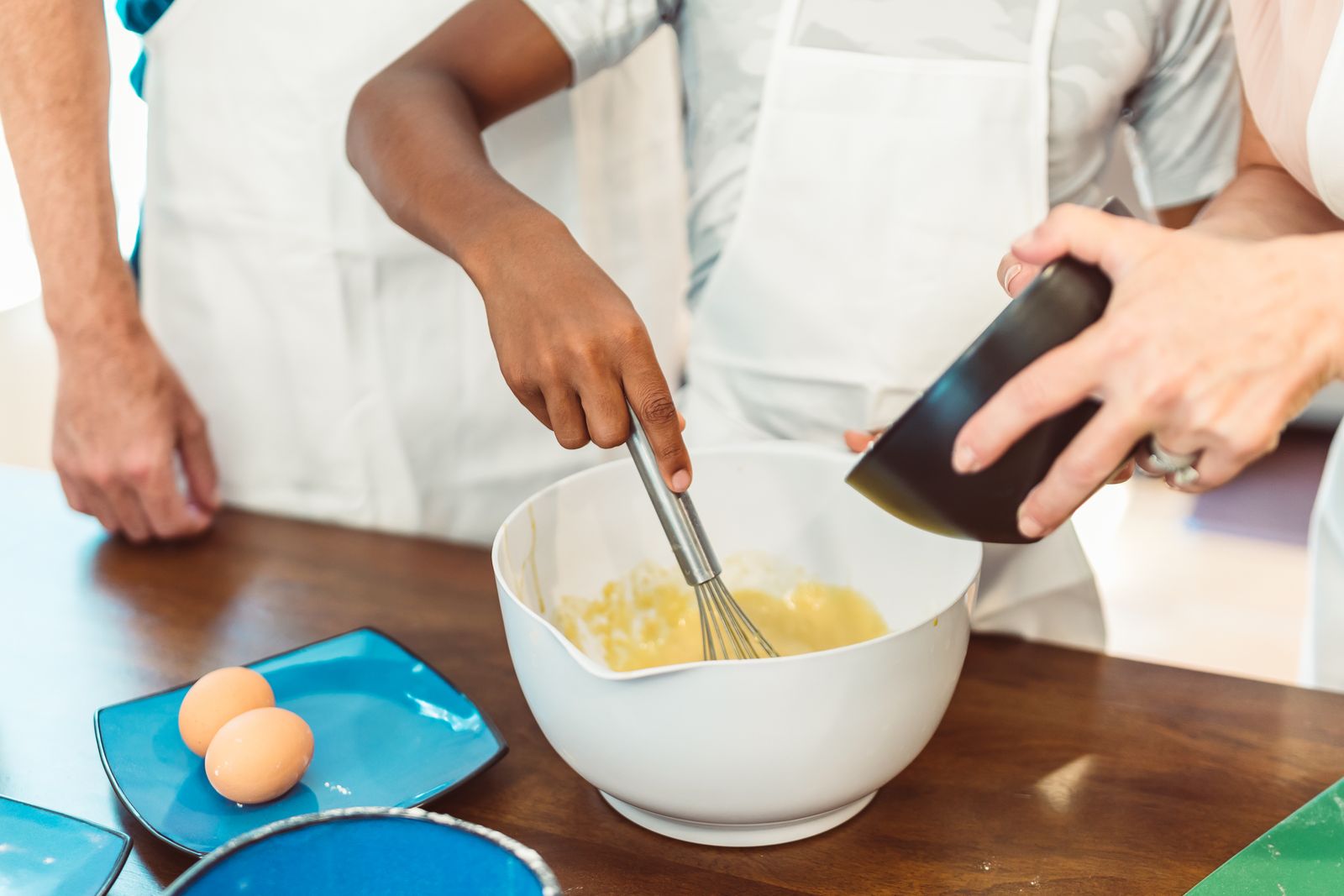 Close-up of two hands whisking batter by hand in a bowl.