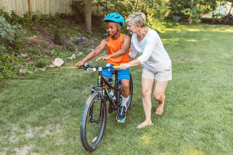 Mother Guiding Her Child To Ride A Bike 