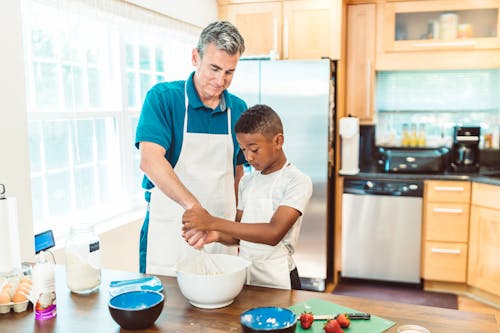 Free Man and a Boy Preparing Food at Home Stock Photo