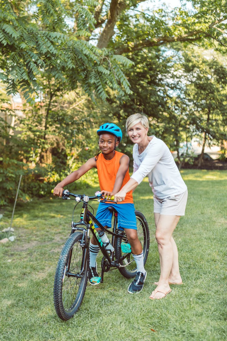 Boy Riding A Bicycle Beside A Woman