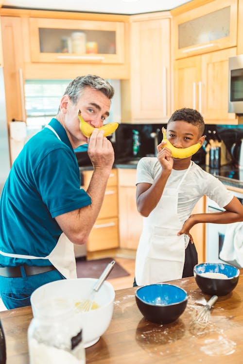 Dad and Son Holding Bananas in the Kitchen