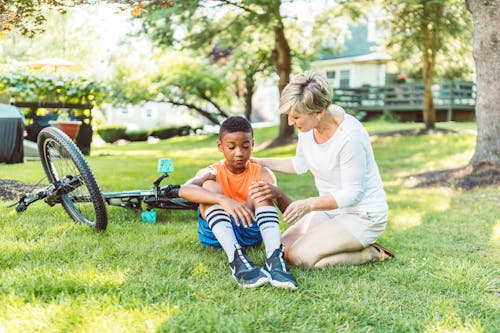 Free Mom Putting Band-Aid on Her Son's Knee Stock Photo