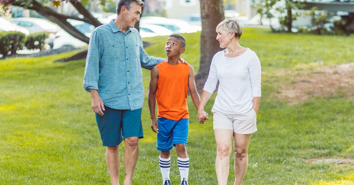 Family of three enjoys a sunny walk in the park, exuding joy and connection.