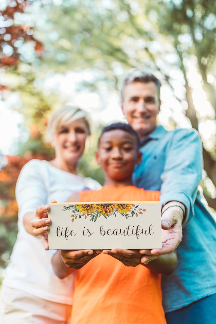 A Family Holding A Printed Paper With A Slogan Life Is Beautiful 