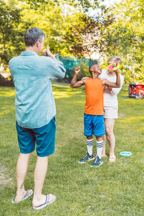 Free Family enjoying a sunny day outdoors playing with a child in a lush park. Stock Photo