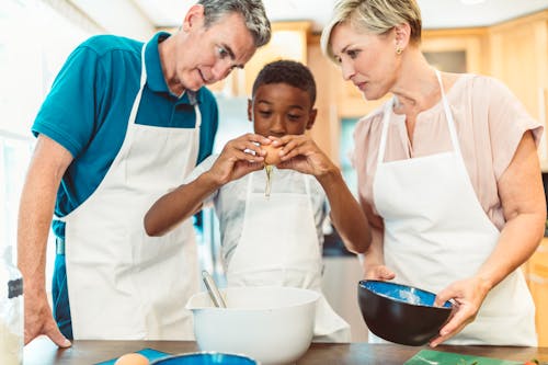 Man and Woman Teaching the Boy How to Bake 