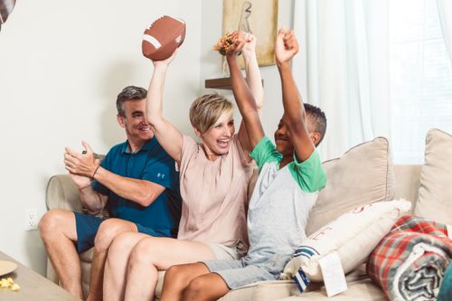 Free Happy family enjoying togetherness and fun indoors, celebrating with a football. Stock Photo