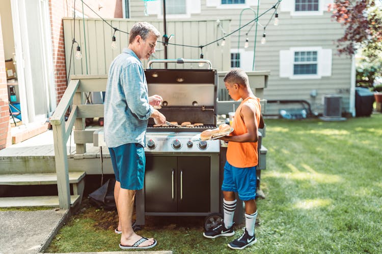 Man And His Adopted Son Cooking Together In The Backyard