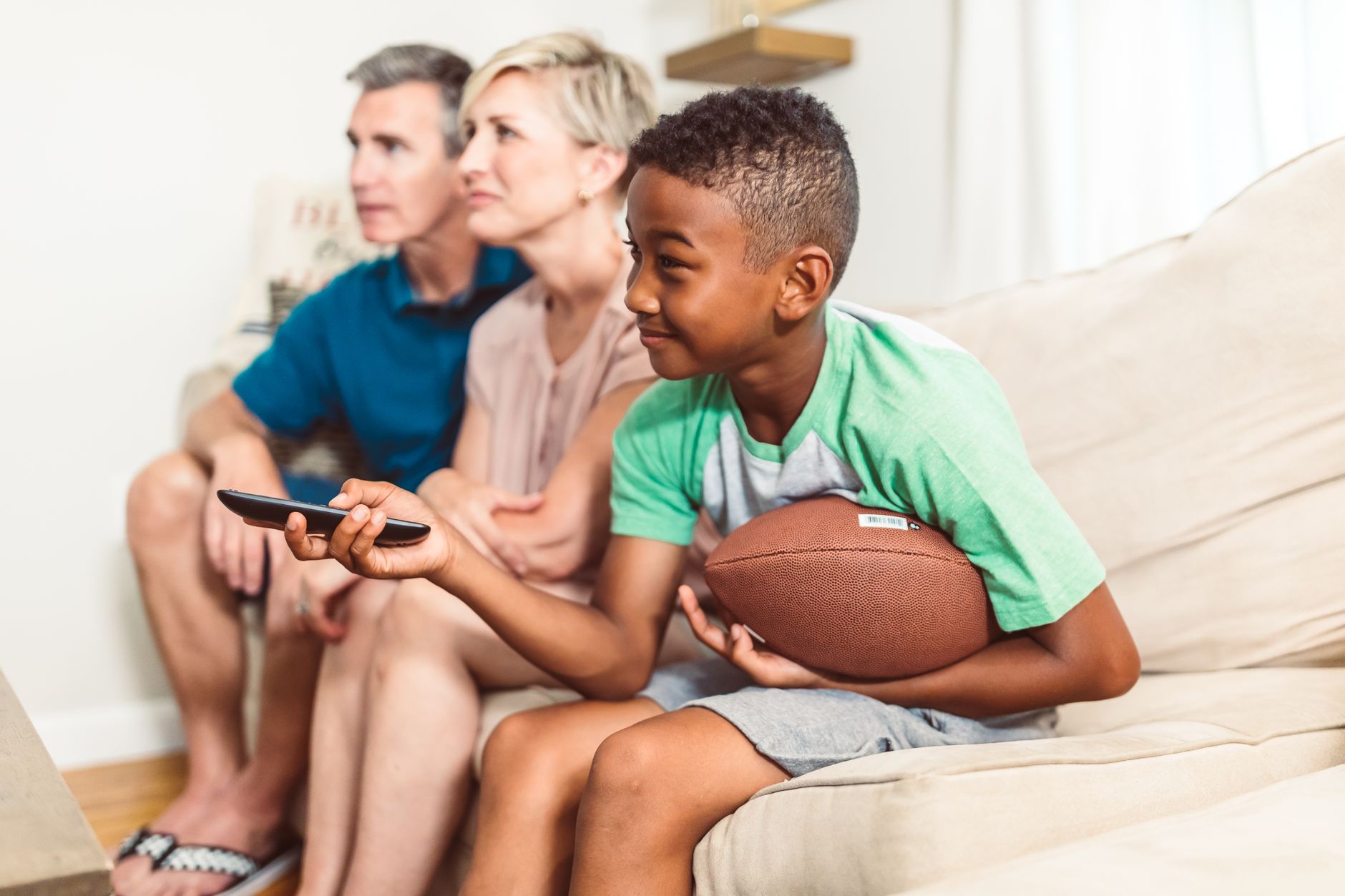 family watching a JioHotstar football broadcast on a living-room television during an evening match