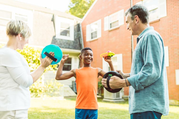 A Family Playing Flying Disc In The Garden