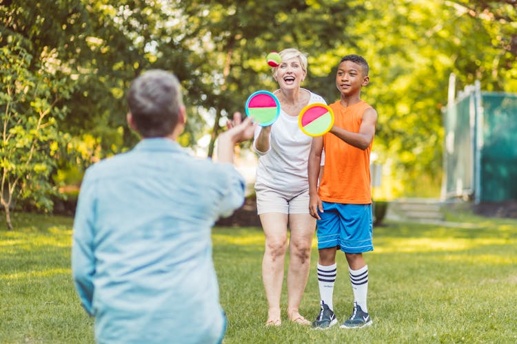 A Woman And A Boy Playing A Toss And Catch Ball Game