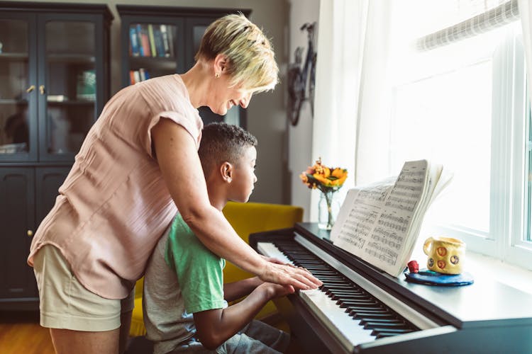 A Woman Teaching The Boy How To Play Piano